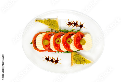 Caprese salad with mozzarella, tomato, basil and balsamic vinegar arranged on white plate