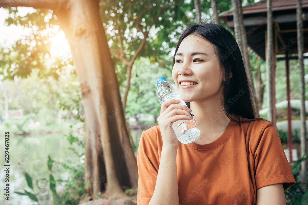 A young or teen asian girl student in university smiling and driking a bottle of cool wather in summer holiday. A young or teen asian girl student in university smiling and driking a bottle of cool wather in summer holiday.