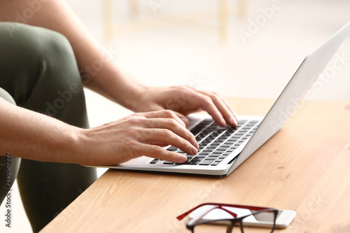 Young man working with laptop at home, closeup