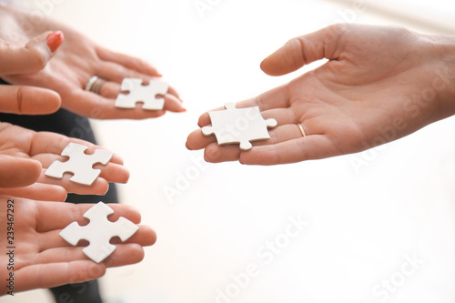 People holding pieces of jigsaw puzzle on white background, closeup