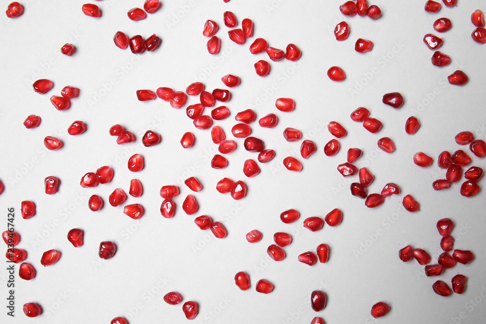 Scattered pomegranate seeds on light background
