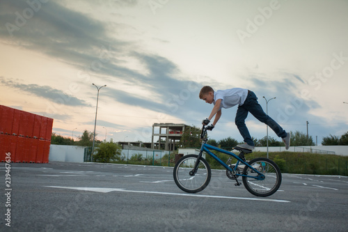 Teen boy riding bicycle standing on one leg