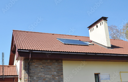 Solar water heater on modern house roof top with skylight, gutter and chimney