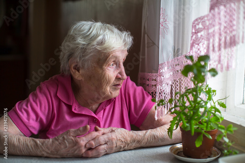 Older woman sitting at the table near the window. © De Visu