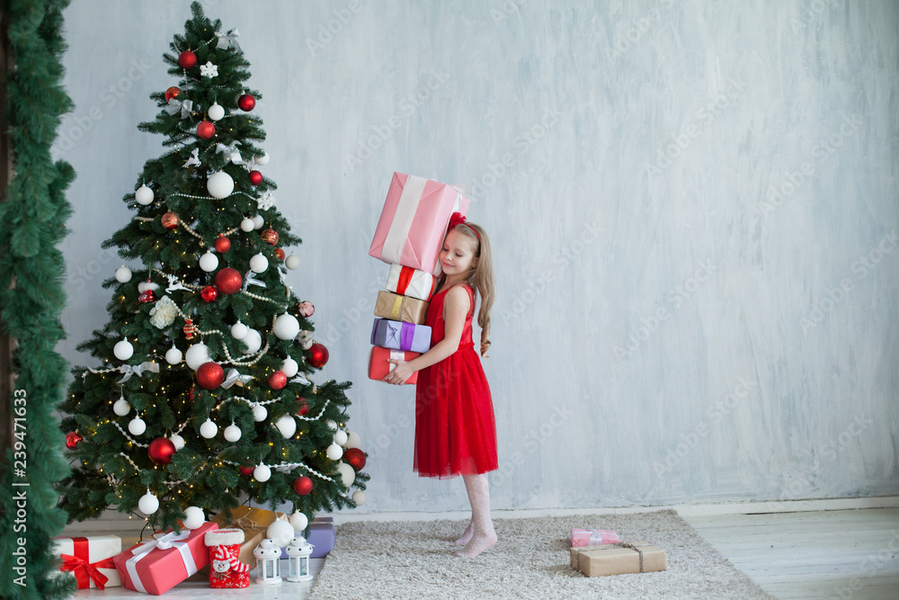 little girl opens Christmas gifts at the Christmas tree new year holiday house