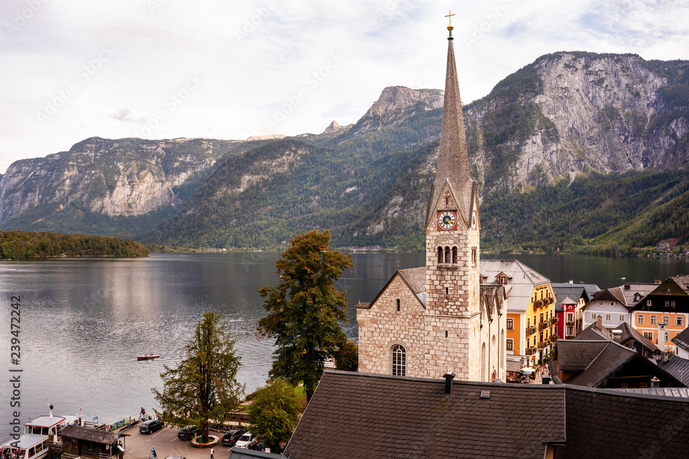 Hallstatt town afternoon photo with its famous church and lake with mountains.