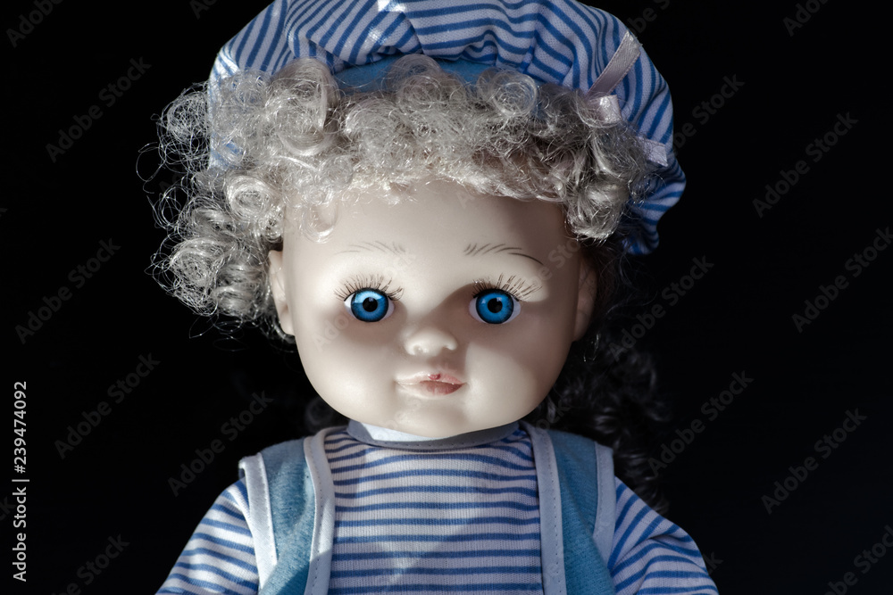Girl doll with bright blue eyes. Sitting doll in blue clothes Girl doll with bright blue eyes. Sitting doll in blue clothes