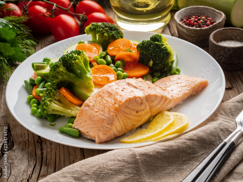 Steam salmon and vegetables, Paleo, keto, fodmap diet. White plate on old rustic wooden table, side view photo