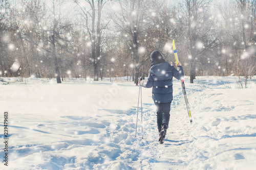 Two teen boys walk with ski in the park in the winter snowfall. Concept of friendships