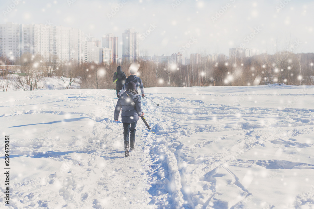 teen boy walk with ski in the park in the winter snowfall. Concept of friendships