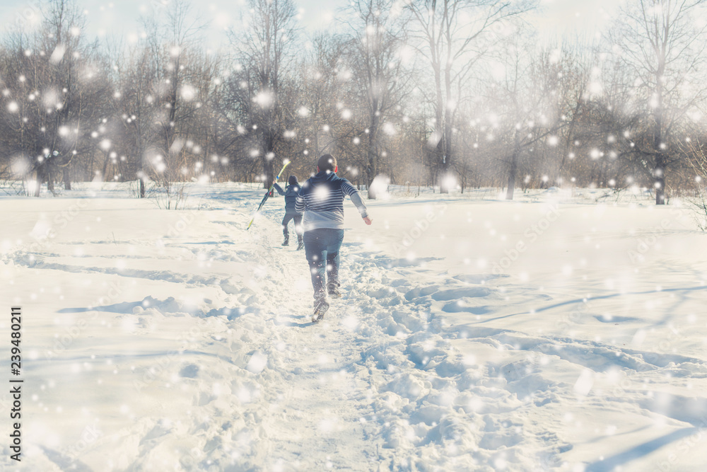 Two teen boys walk with ski in the park in the winter snowfall. Concept of friendships