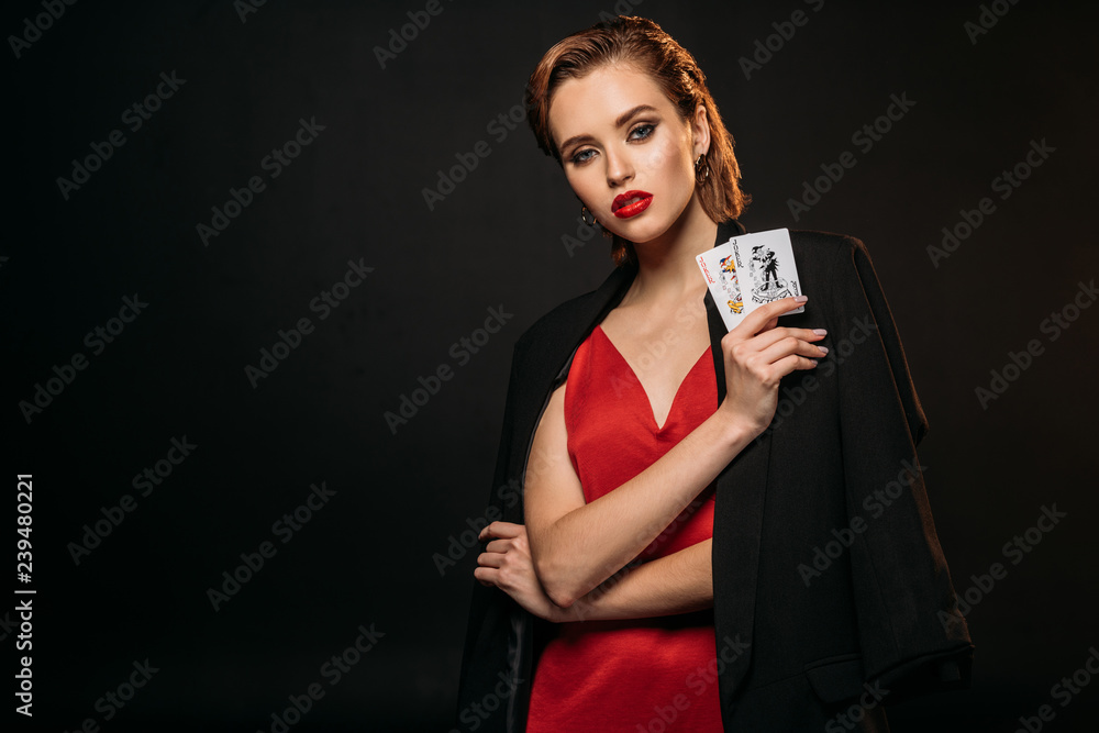 Φωτογραφία beautiful girl in red dress and black jacket holding playing cards and looking a