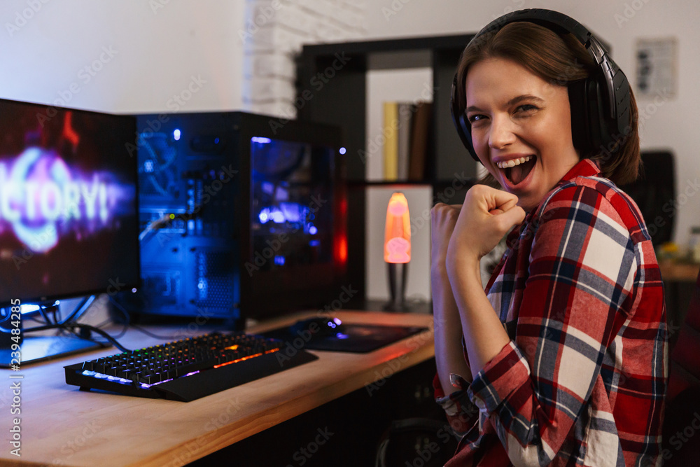 Excited girl gamer sitting at the table, playing online games Excited girl gamer sitting at the table, playing online games