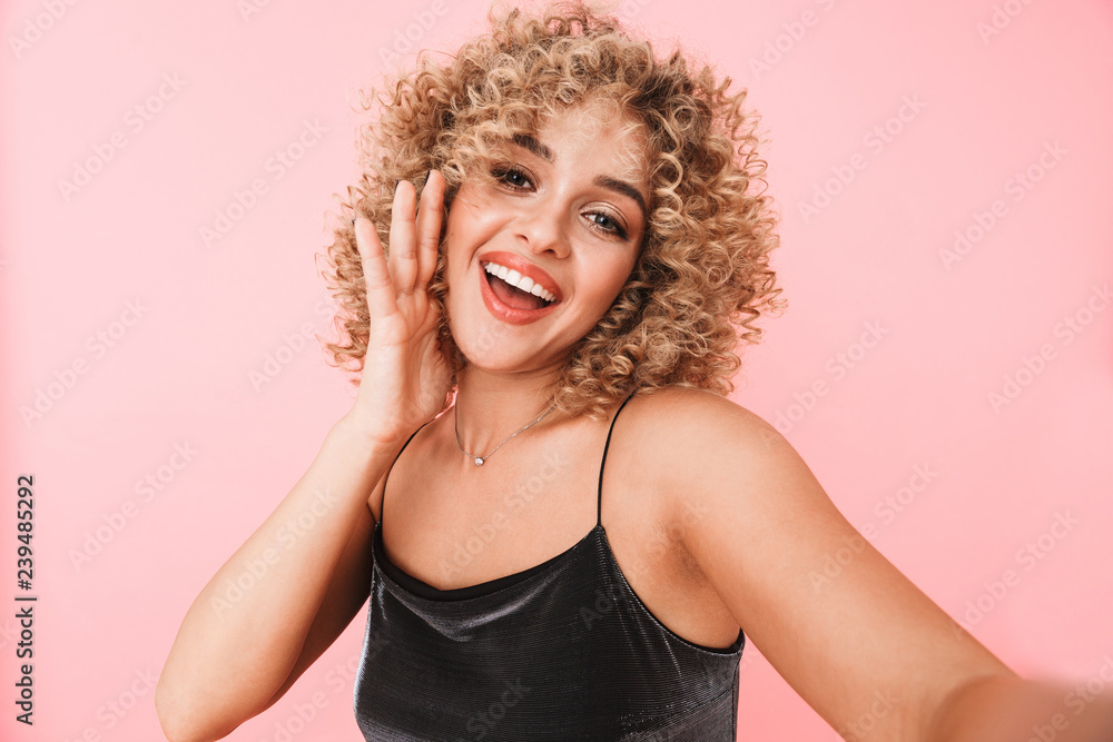 Portrait of adorable curly woman 20s smiling and taking selfie photo, isolated over pink background Portrait of adorable curly woman 20s smiling and taking selfie photo, isolated over pink background
