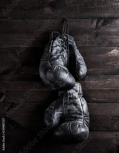  black leather boxing gloves hanging on a nail © nndanko