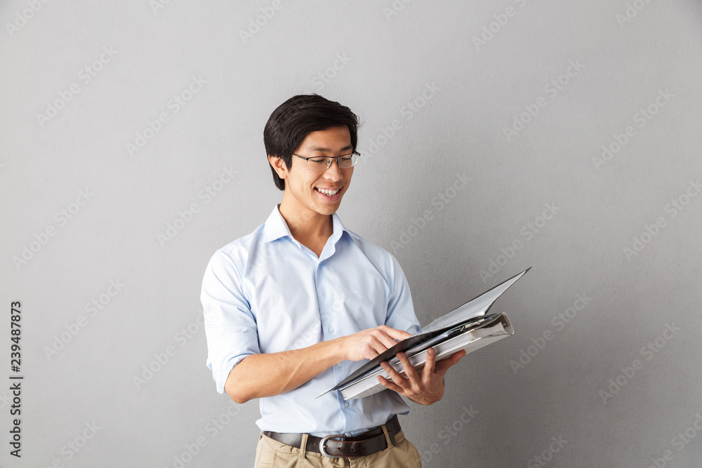 Happy asian man standing isolated over gray Happy asian man standing isolated over gray