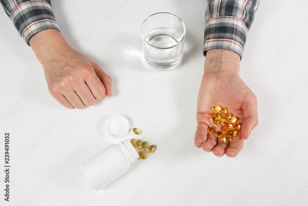Obraz premium Man hand holds yellow medication capsules of omega 3
