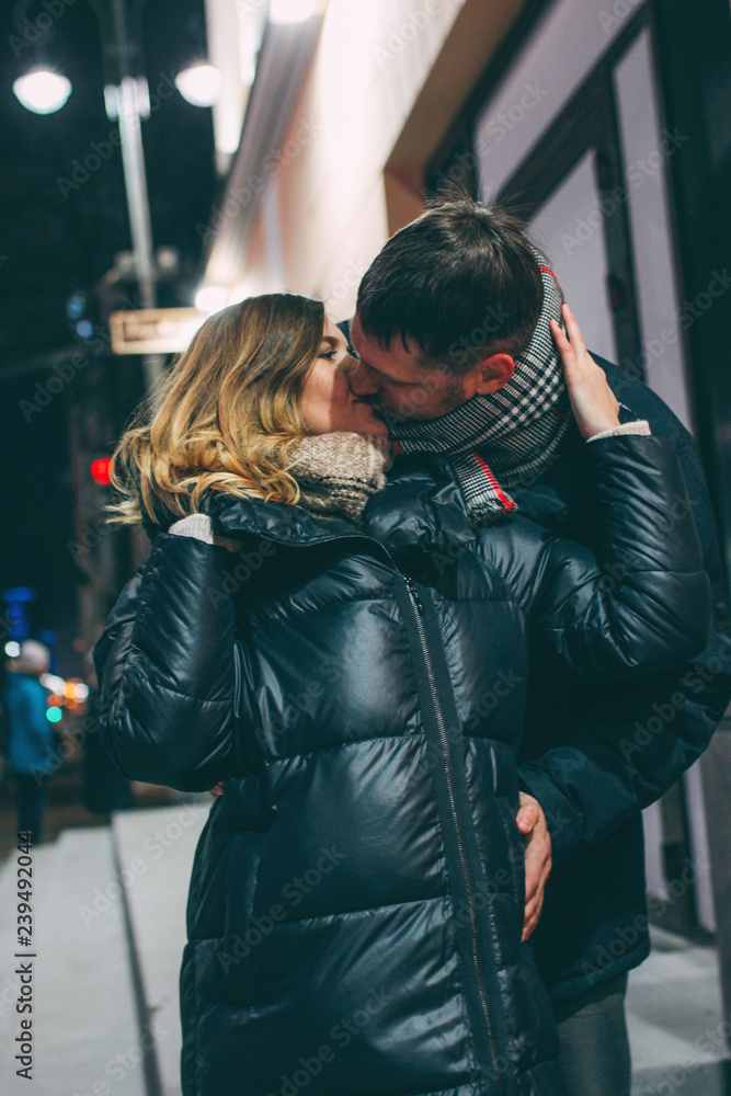 Real young couple walking together in night city, kissing and sm Real young couple walking together in night city, kissing and sm