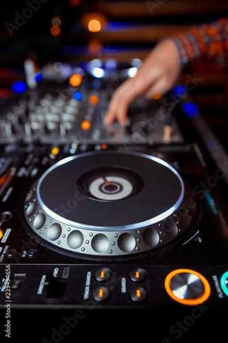 Dj mixes the track in the nightclub at party. In the background laser light show