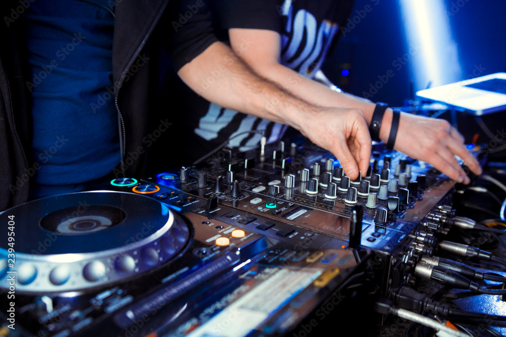 Dj mixes the track in the nightclub at party. In the background laser light show Dj mixes the track in the nightclub at party. In the background laser light show