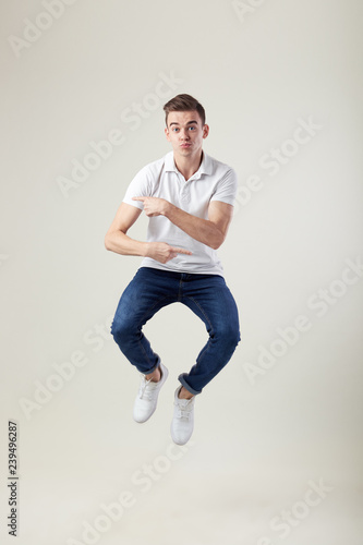 Happy guy dressed in a white t-shirt and jeans jumps in the studio on a white background