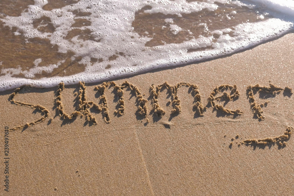 Fototapeta premium Word Summer written in the sea sand. Waves washed away the inscription.