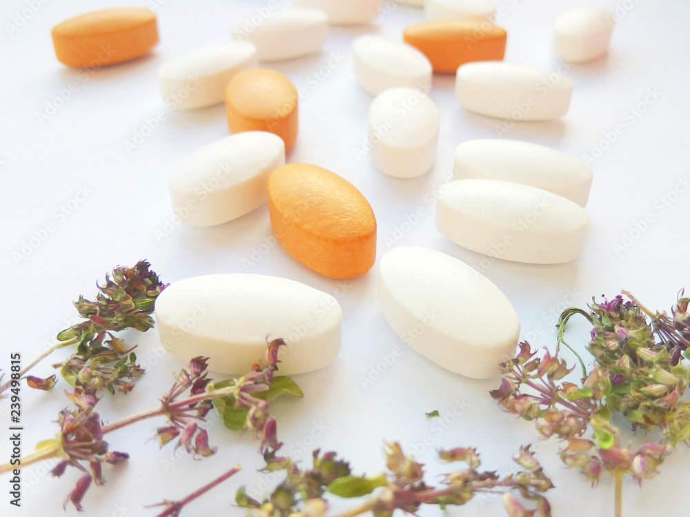 Herbal medicine pills with dry natural herbs on white background. Concept of herbal medicine and dietary supplements, biologically active additives and vitamins. Close up photography