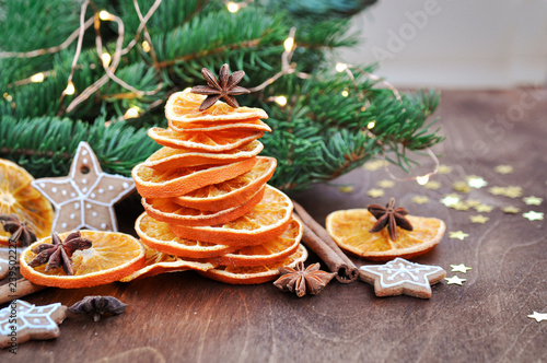 Holiday card for the new year is 2019 in warm, trendy colors. Christmas tree of orange slices, cinnamon, anise and confetti stars on rustic wooden background.