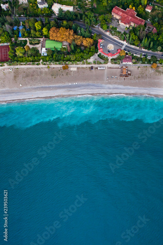 Fototapeta Naklejka Na Ścianę i Meble -  Hotels among the green park on the seafront with turquoise water and the beach. top down