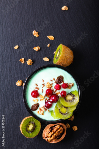 Healthy food colorful Yogurt Breakfast Bowl  with kiwi, flax seeds, Granola, and red currants in black ceramic bowl with copy space