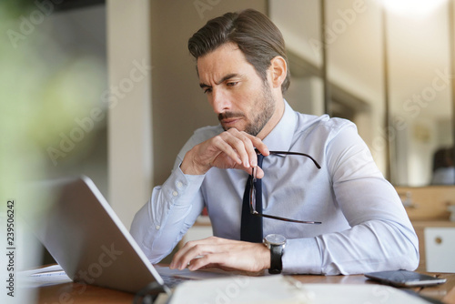 Attractive businessman concentrating on laptop in office