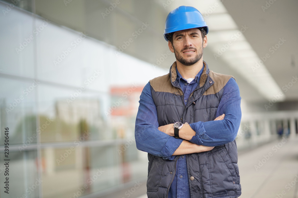Industrial worker in hardhat infront of modern building Industrial worker in hardhat infront of modern building
