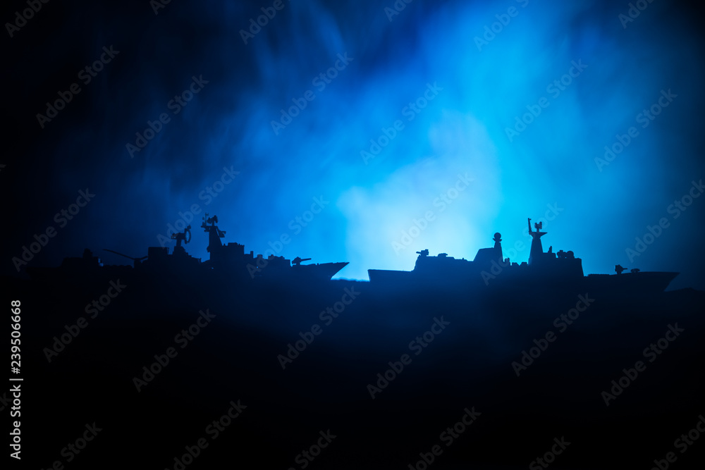 Sea battle scene. Silhouette of military war ship on dark foggy toned sky background. Dramatic war scene with Explosion and fire as decoration. Sea battle scene. Silhouette of military war ship on dark foggy toned sky background. Dramatic war scene with Explosion and fire as decoration.
