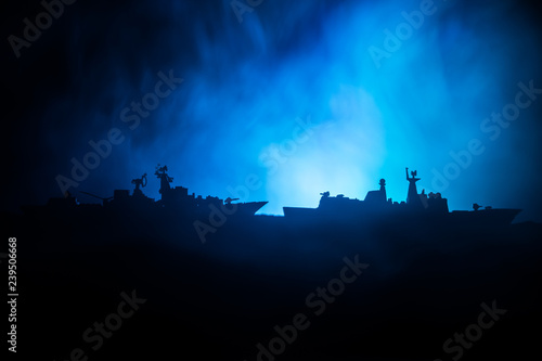 Sea battle scene. Silhouette of military war ship on dark foggy toned sky background. Dramatic war scene with Explosion and fire as decoration.