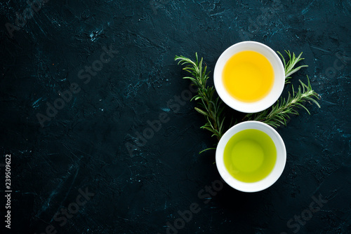 Olive oil, sunflower oil and rosemary. On a black stone background. Top view. Free copy space.