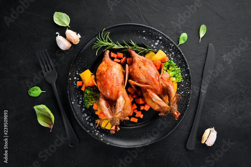 Baked quail. On a black background. Top view. Free space for your text.
