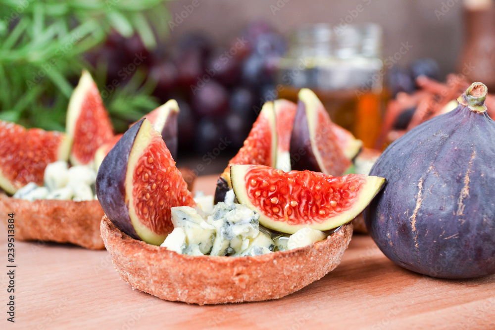 Festive appetizer. Rye flour tarts with gorgonzola cheese, fig fruit slices and honey. Healthy food concept. Perfect combination of cheese, fruits and honey syrup. Festive appetizer. Rye flour tarts with gorgonzola cheese, fig fruit slices and honey. Healthy food concept. Perfect combination of cheese, fruits and honey syrup.