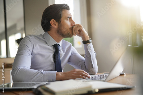 Handsome businessman in modern office looking out photo