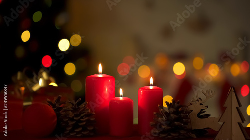 Big festive candles burning near Christmas decorations  lights on background