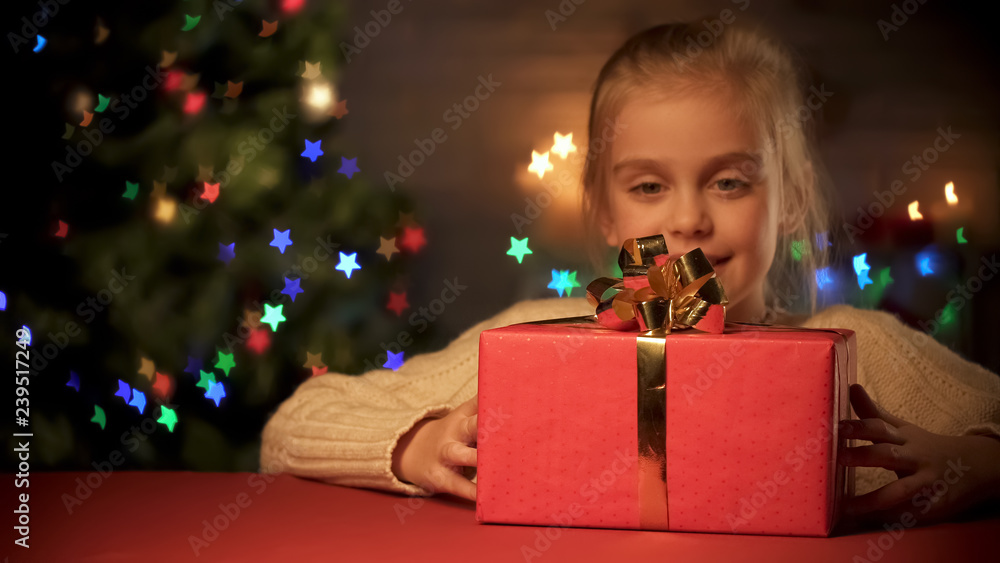 Cute girl admiring red gift box with big golden bow, child dreams, xmas magic Cute girl admiring red gift box with big golden bow, child dreams, xmas magic
