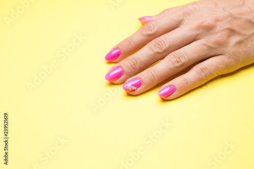 Stylish manicure pink on a yellow background