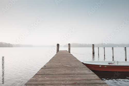 rotes Ruderboot an einem Holzsteg im Spreewald. Aufgenommen an einem nebeligen Tag im Spätherbst.