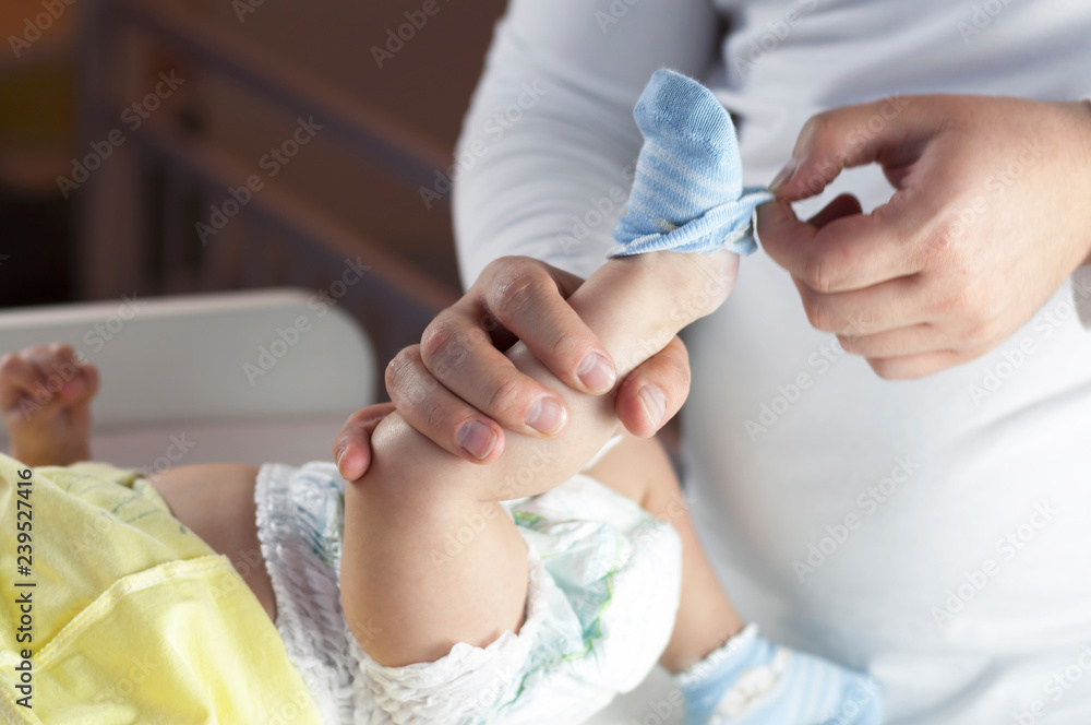 Young dad changes the diaper and clothes to his newborn small child. Selective focus. Young dad changes the diaper and clothes to his newborn small child. Selective focus.