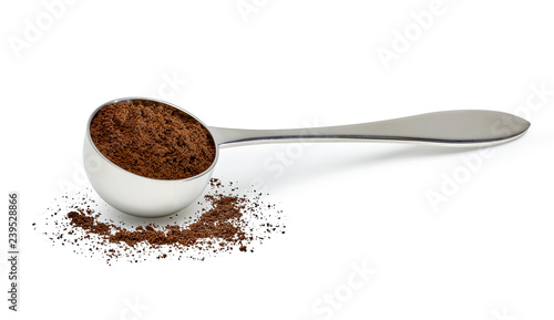 Grinded coffee powder in measuring scoop with beans isolated on white background