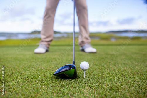 golf club and golf ball on tee, focus on the head of the club and ball.