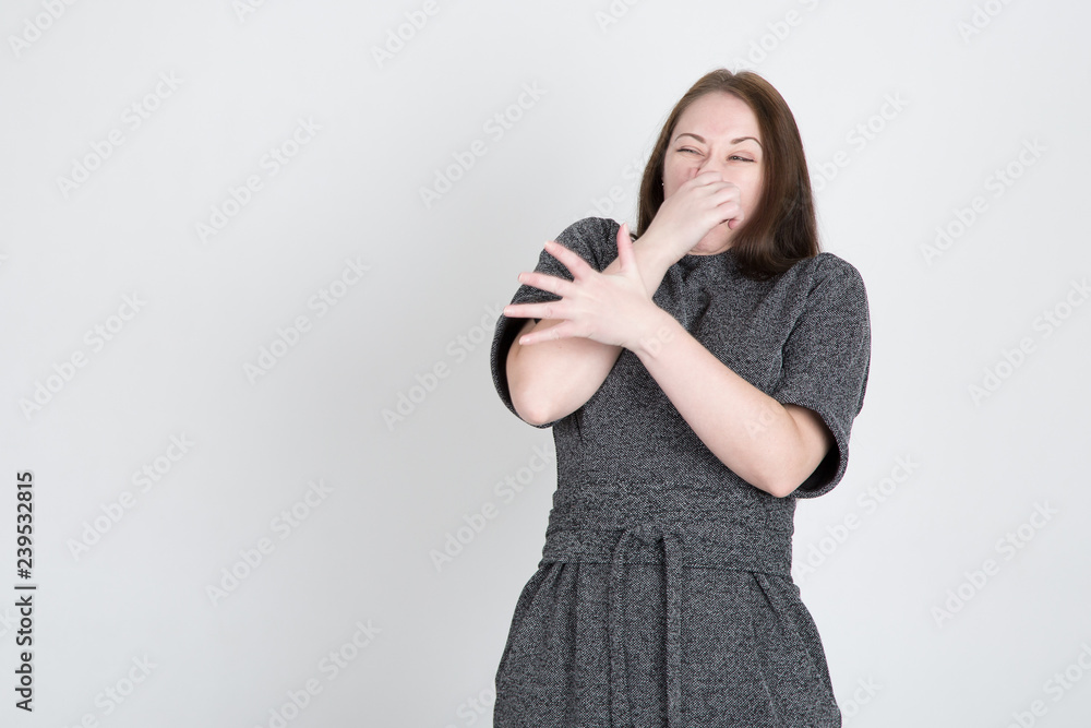 a young woman clamps her nose and pushes something away from her a young woman clamps her nose and pushes something away from her