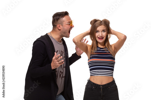 Young emotional man and woman quarrel. Man screaming at the woman waving her arms, the girl covered her ears