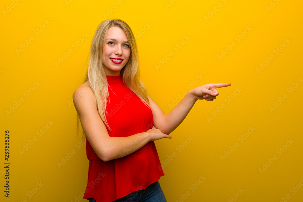 Young girl with red dress over yellow wall pointing finger to the side in lateral position Young girl with red dress over yellow wall pointing finger to the side in lateral position