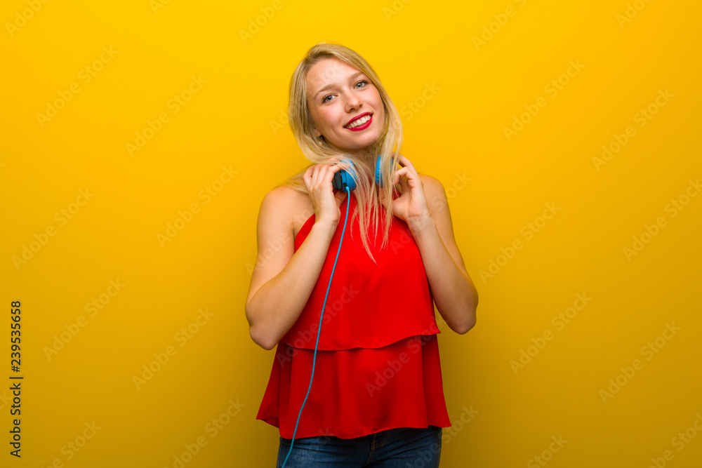 Young girl with red dress over yellow wall with headphones Young girl with red dress over yellow wall with headphones