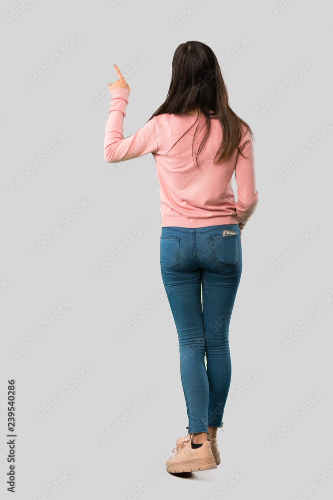 Φωτογραφία Full body of Teenager girl with pink shirt pointing back with the index finger o